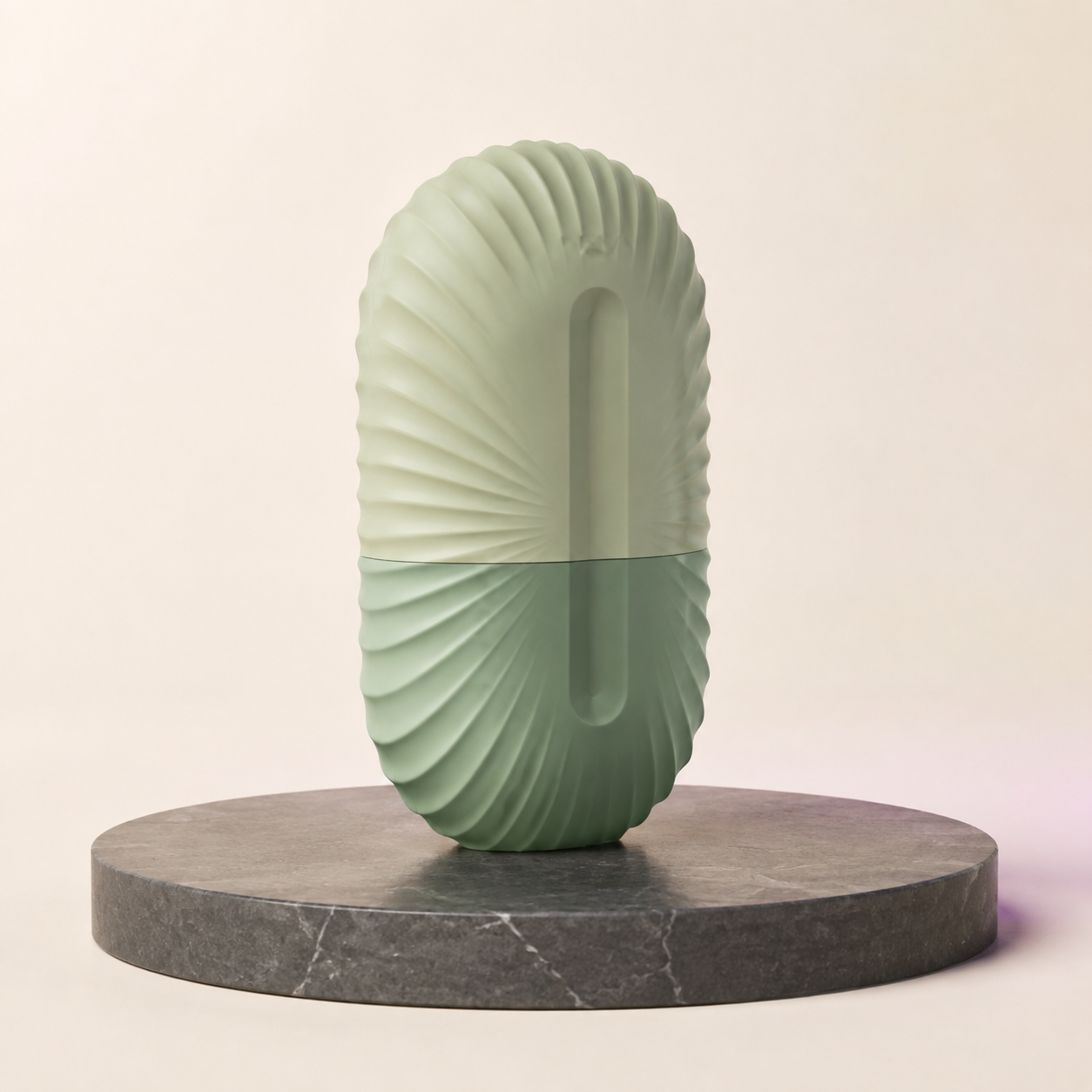 Muted sage ribbed silicone facial ice mold on a charcoal stone surface